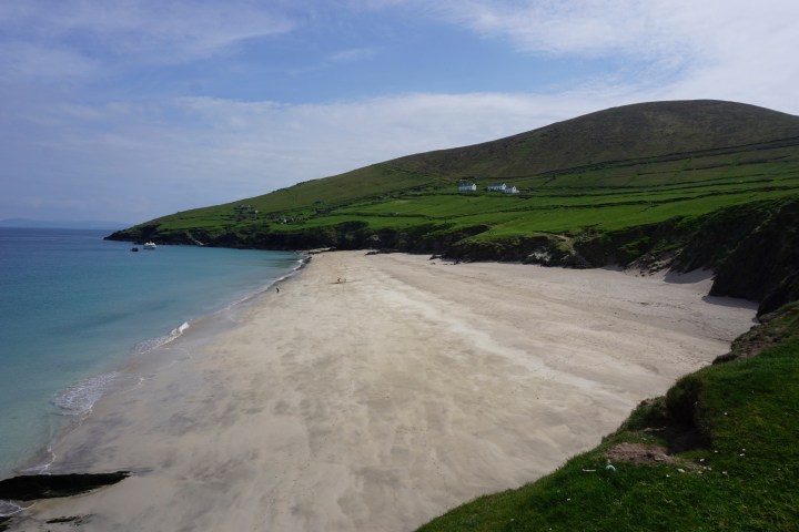 a close up of a hillside next to a body of water with Keem Bay in the background